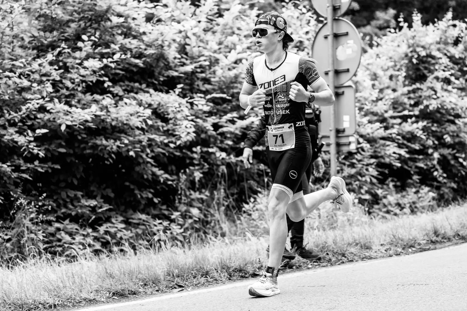 Oliver running on the road with race number 71. Black and white.