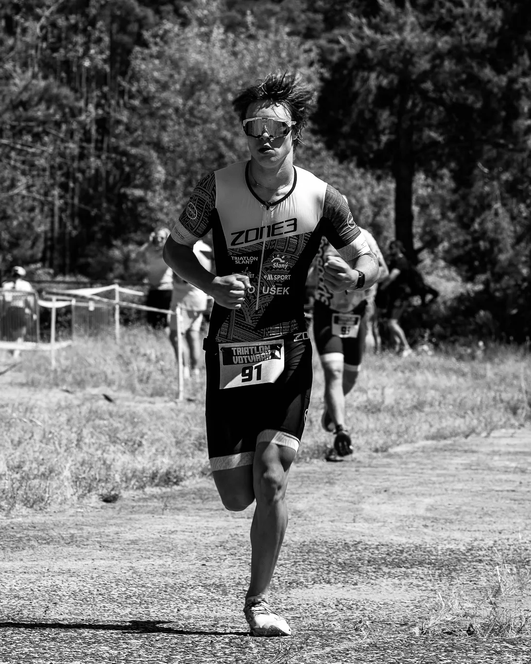 Oliver running towards the camera with race number 91. Black and white.